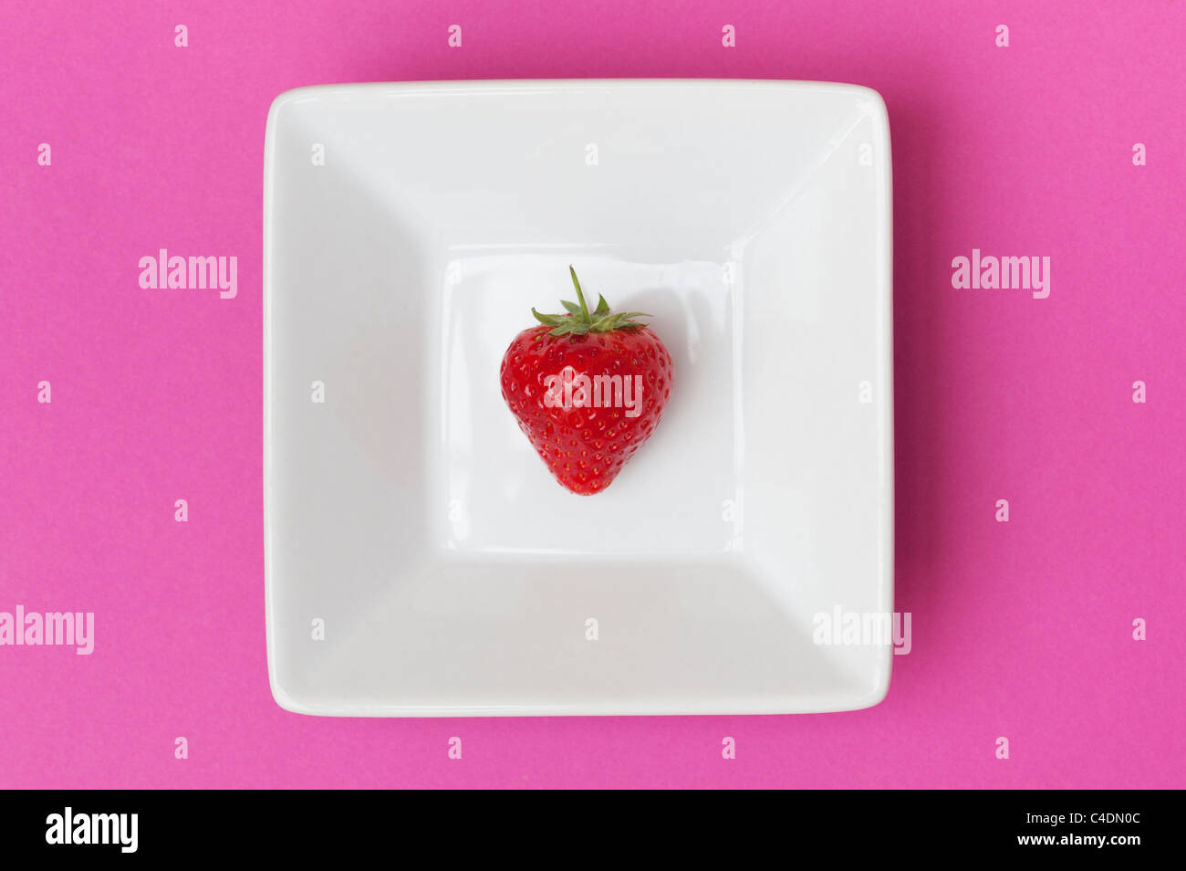 Strawberry in a square ceramic dish on a pink background Stock Photo