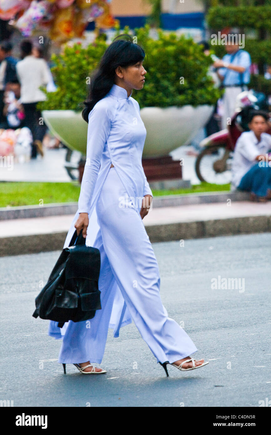Woman in white Ao Dai crossing the street Stock Photo