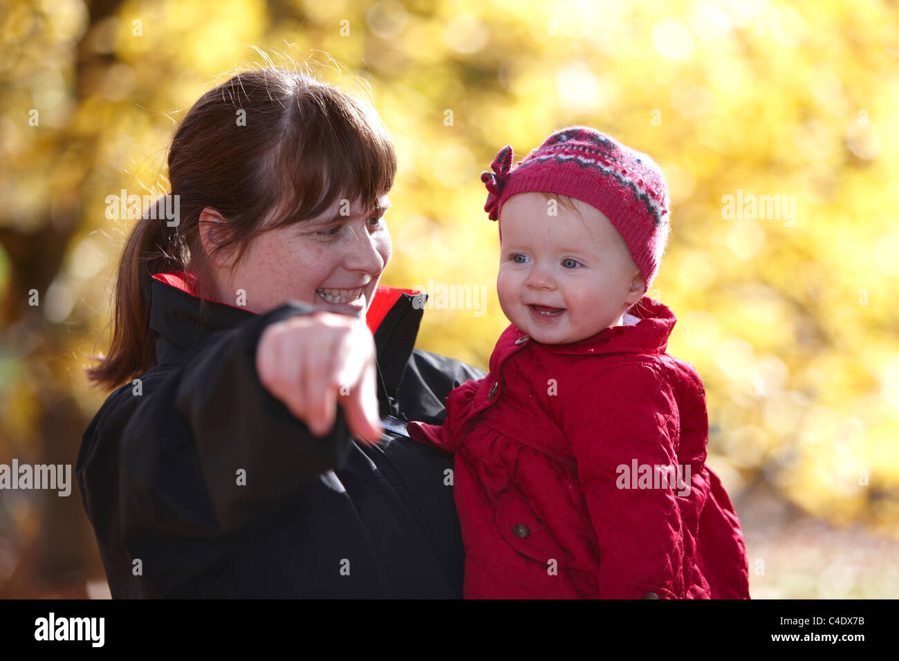 8 Month old baby girl in park in autumn with leaves around Stock Photo