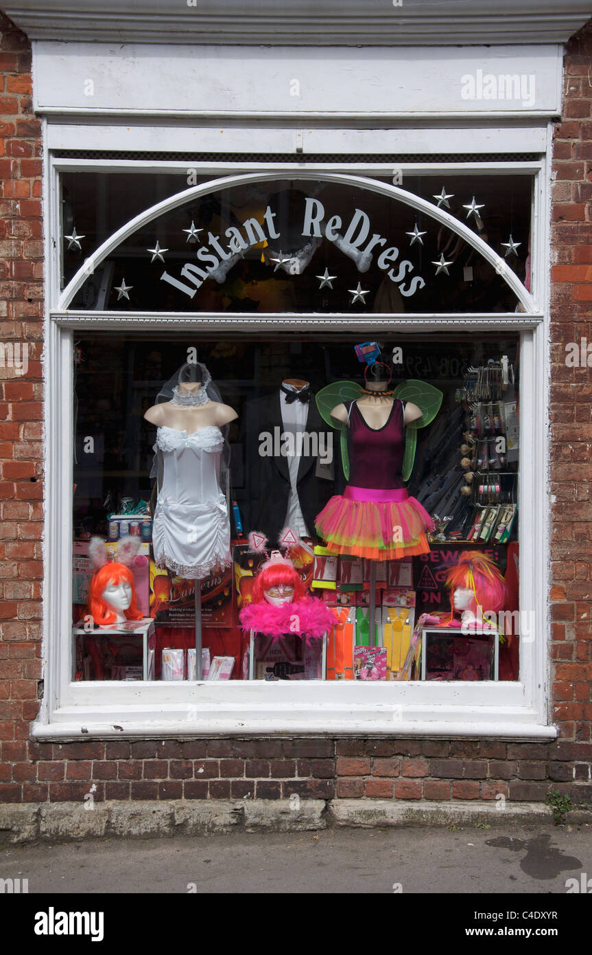 The colourful window display of the fancy dress and novelty goods shop, “Instant ReDress”. Bridport, Dorset, England, United Kingdom. Stock Photo
