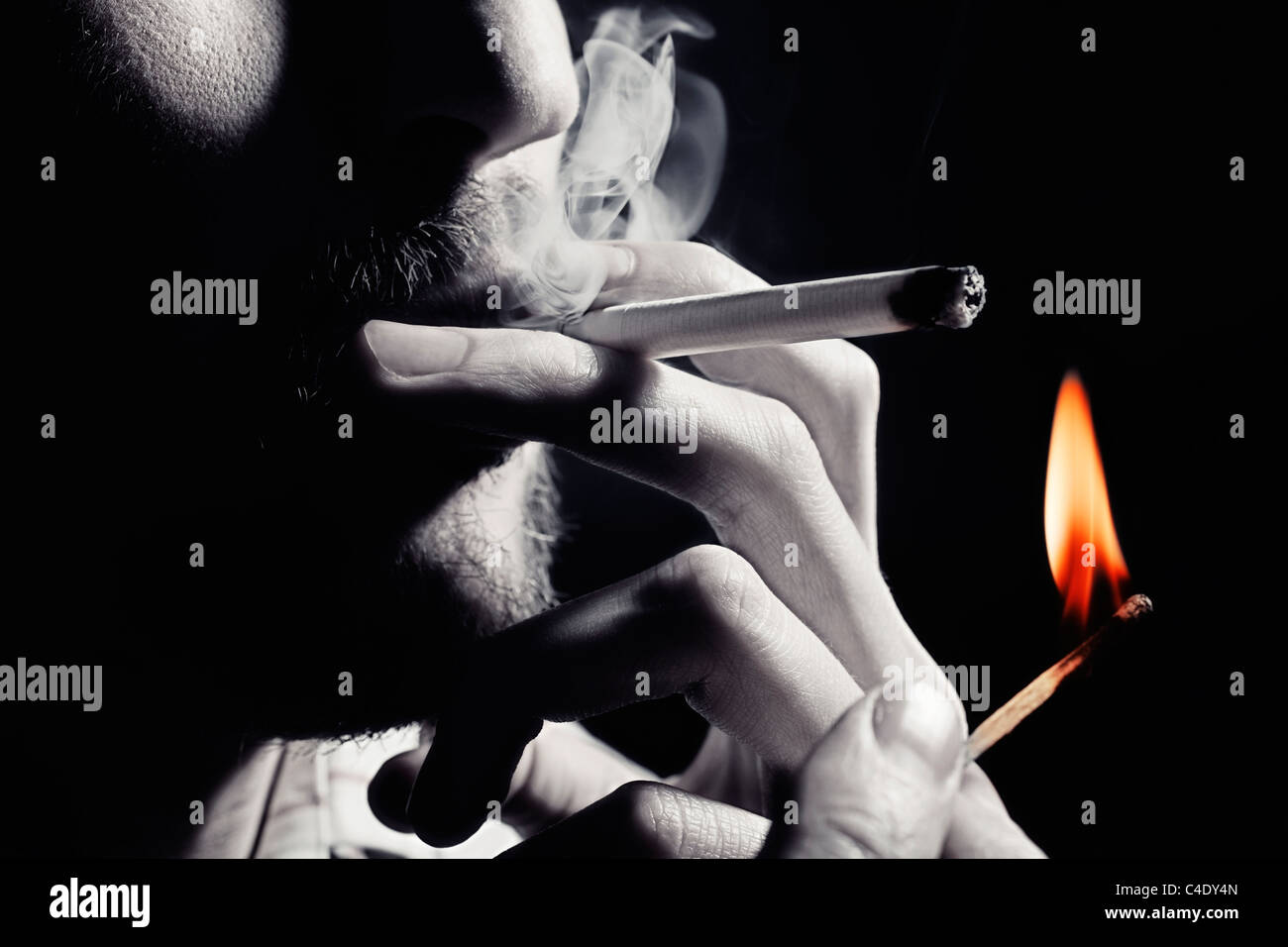 Men's hand lights a cigarette with a match closeup Stock Photo