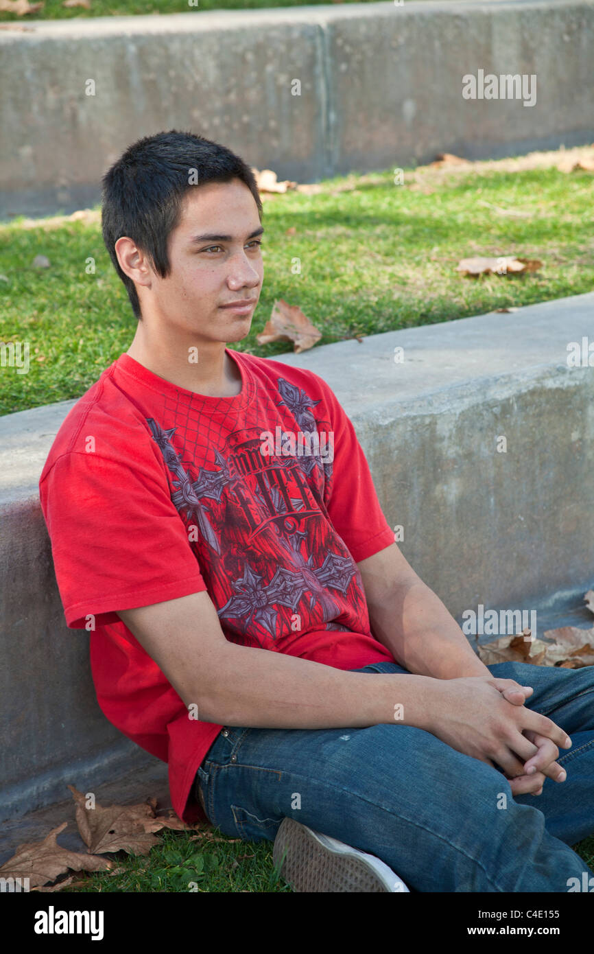 15-18 year old olds Young man. Blackfoot American Native American meditating prayerful thoughtful dreaming thinking sitting alone park. MR © Myrleen P Stock Photo