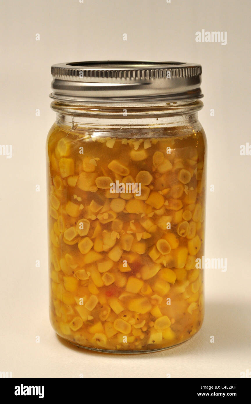 A jar of home made canned corn relish sits on a white background. Stock Photo