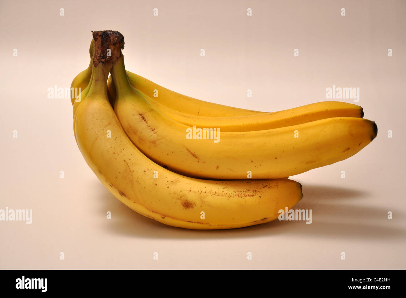 A brunch of banana's lays on top of a white background. Stock Photo