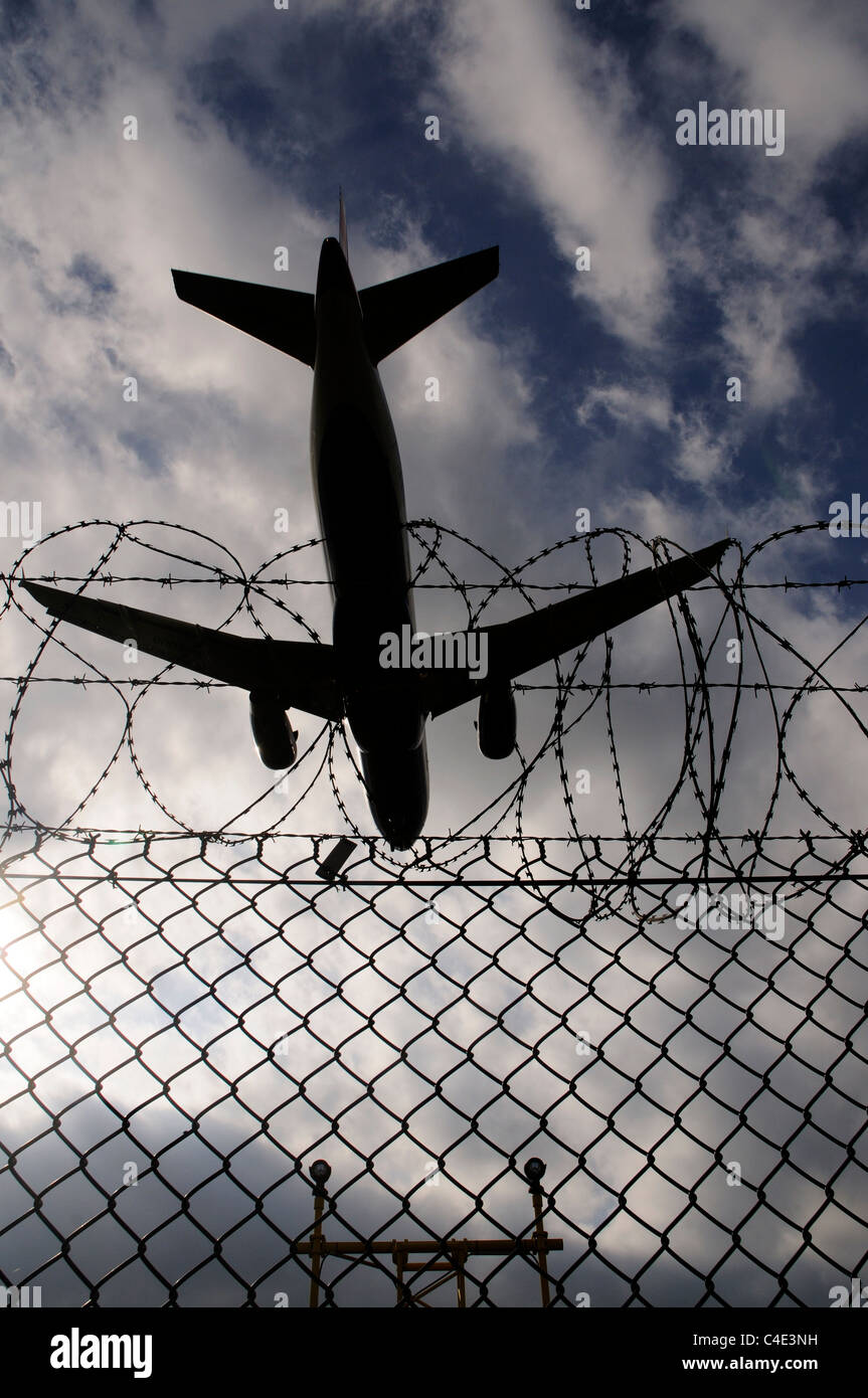 A landing plane crossing the barbed wire perimeter fence at Heathrow Airport Stock Photo