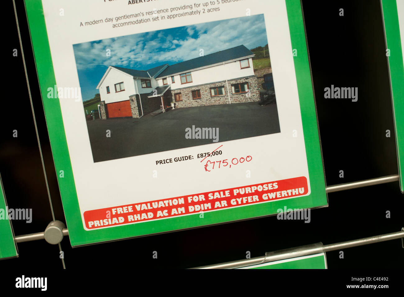 Details of a £100,000 Price reduction on a luxury detached house in an estate agents window. Wales UK Stock Photo