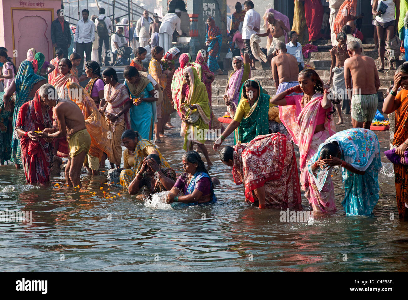 Women taking the ritual bath in the sacred waters of the Godavari river. Ram Kund. Nasik. India Stock Photo