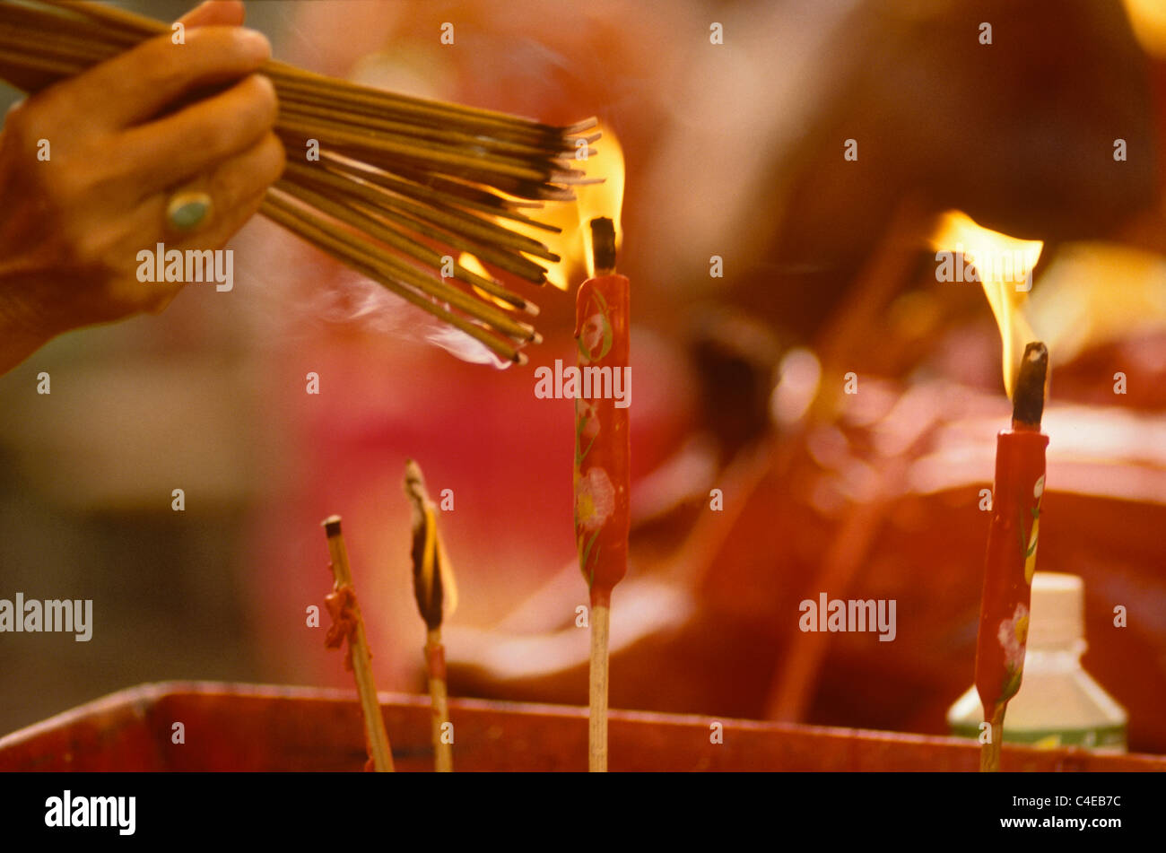 Bundles of incense are lit using candles and then placed standing up in