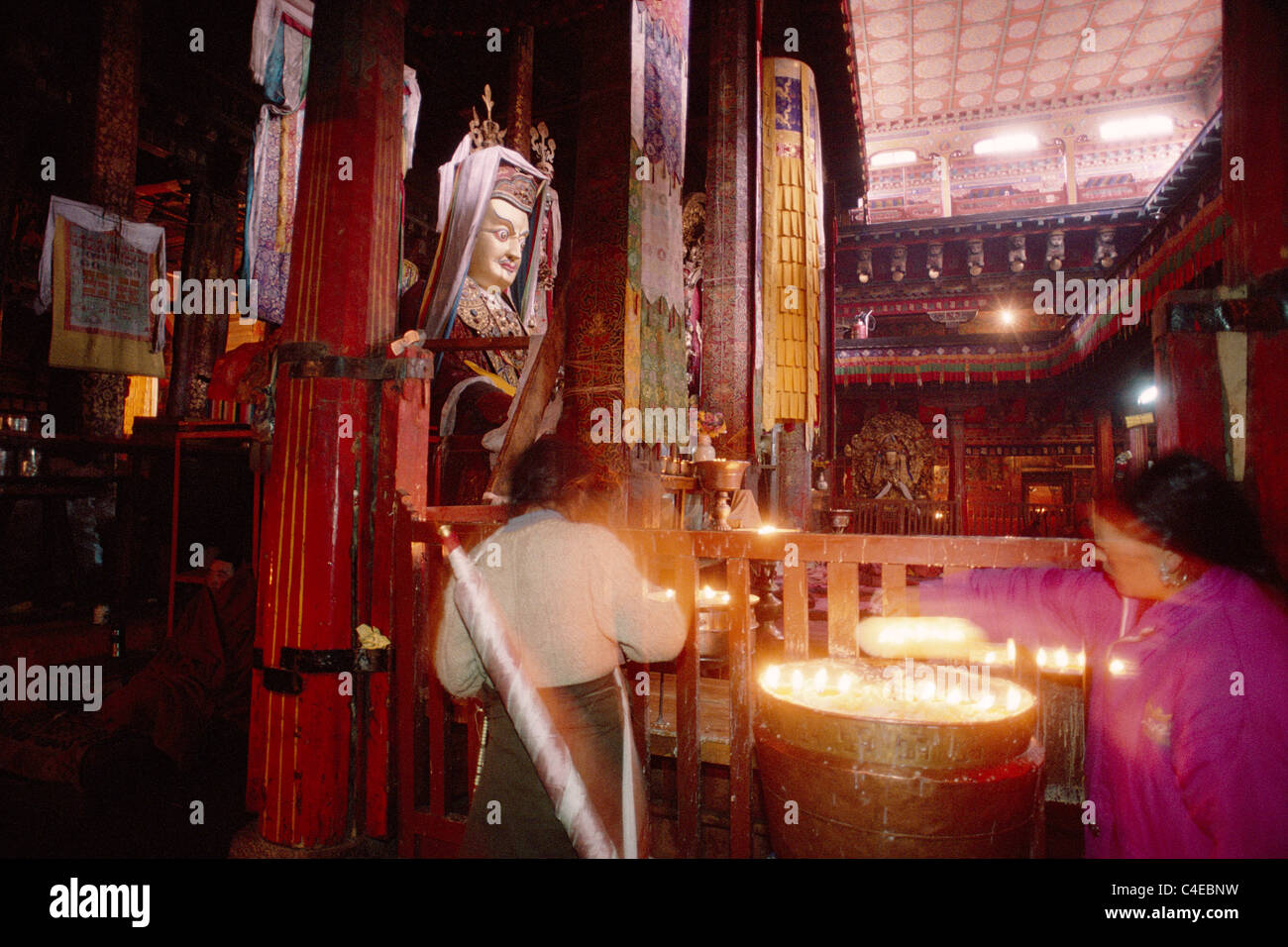 Tibetan pilgrims light butter candles in front of a statue of Guru
