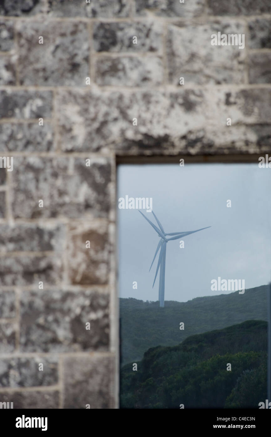 wind generators reflected in window of old stone house Stock Photo