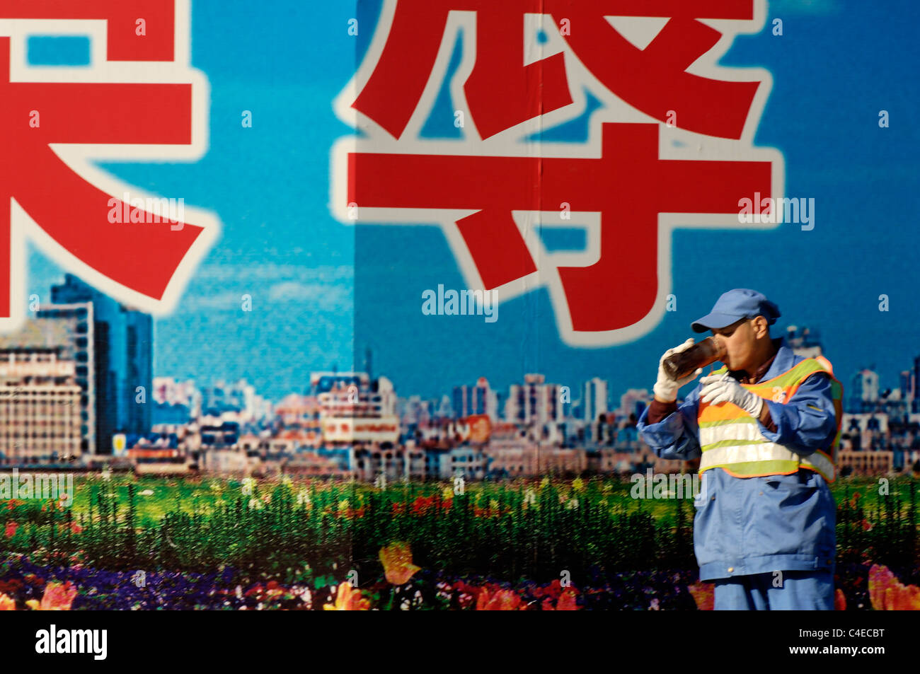 Sreeet cleaner in front of billboards erected around a building site, downtown Shanghai near the Bund, China. Stock Photo