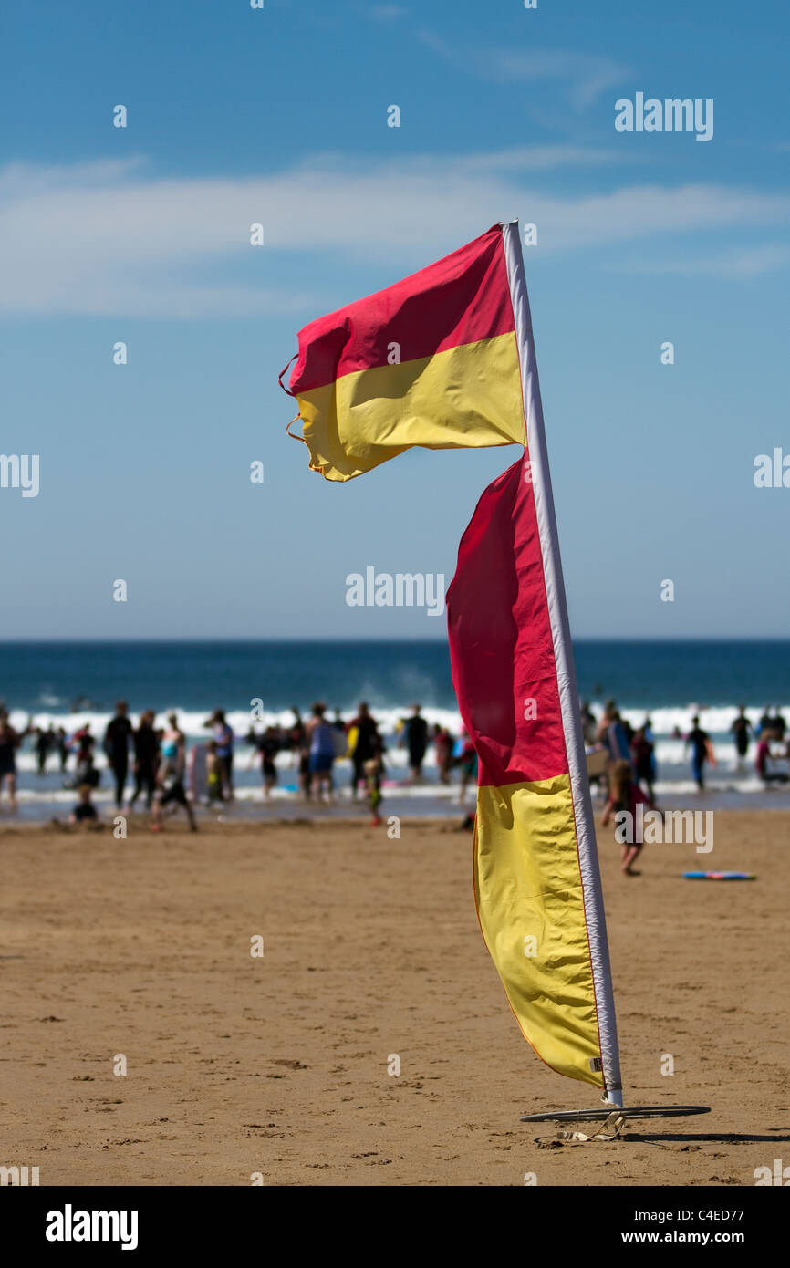 Warning Flag markers on the Blue flag sandy beach, as summer surfers take to the sea in dangerous conditions at Woolacombe Bay Beach, Devon, UK Stock Photo