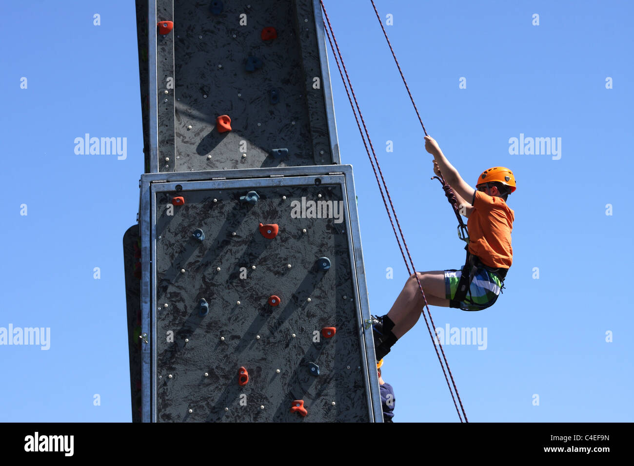 A young preschool boy climbing on an outdoor climbing wall for fun, a