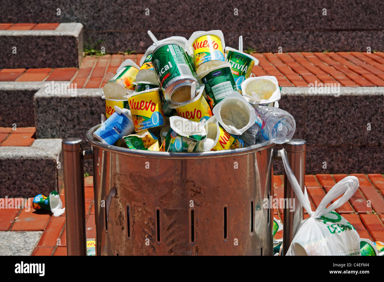 Plastic yoghurt pots in litter bin following free tasting in Street in