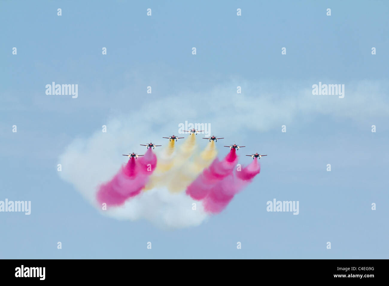 A team of seven airplanes on an air show releasing red and yellow smoke Stock Photo