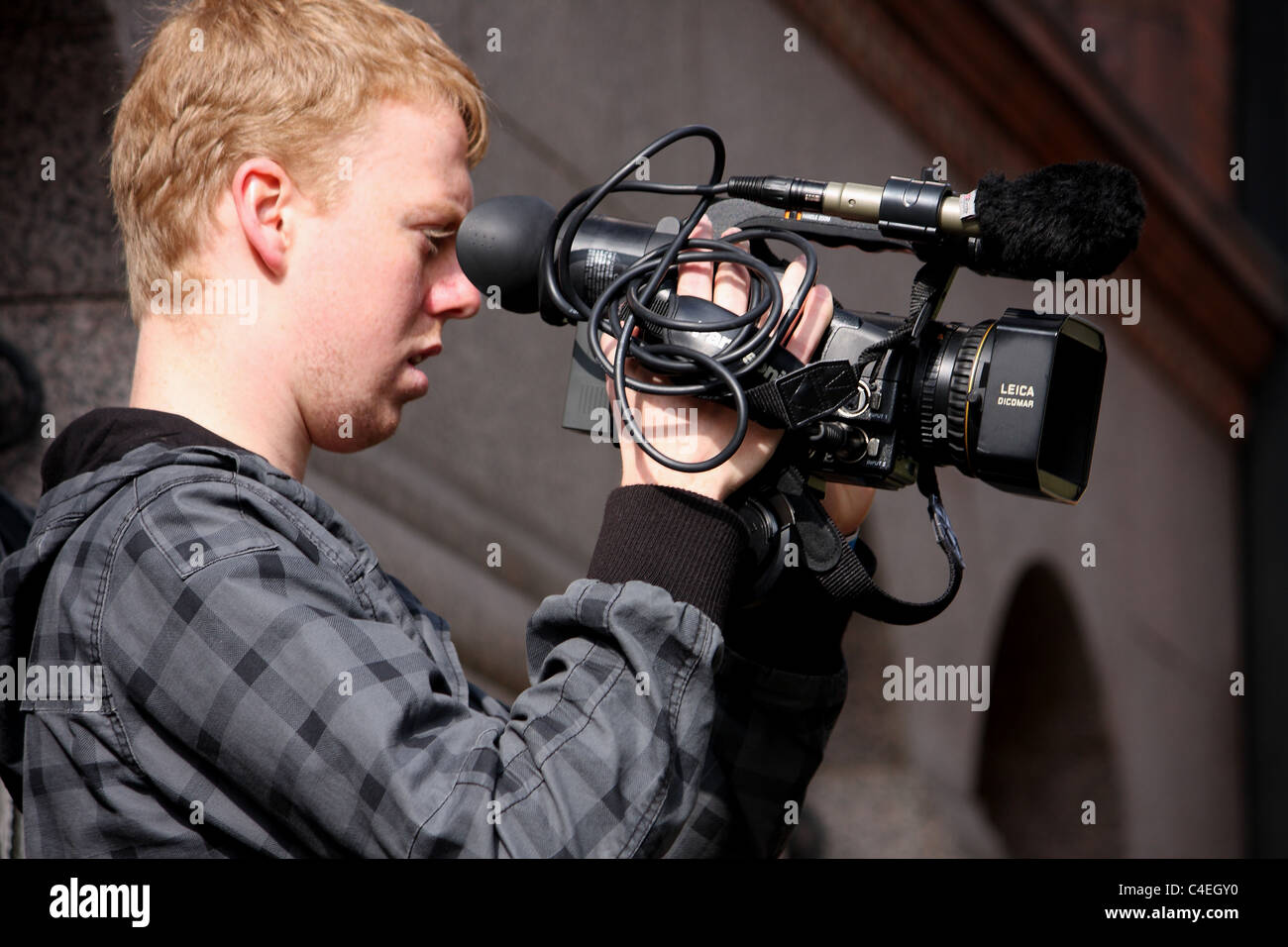 A young teenage boy possibly on work experience filming news. Stock Photo