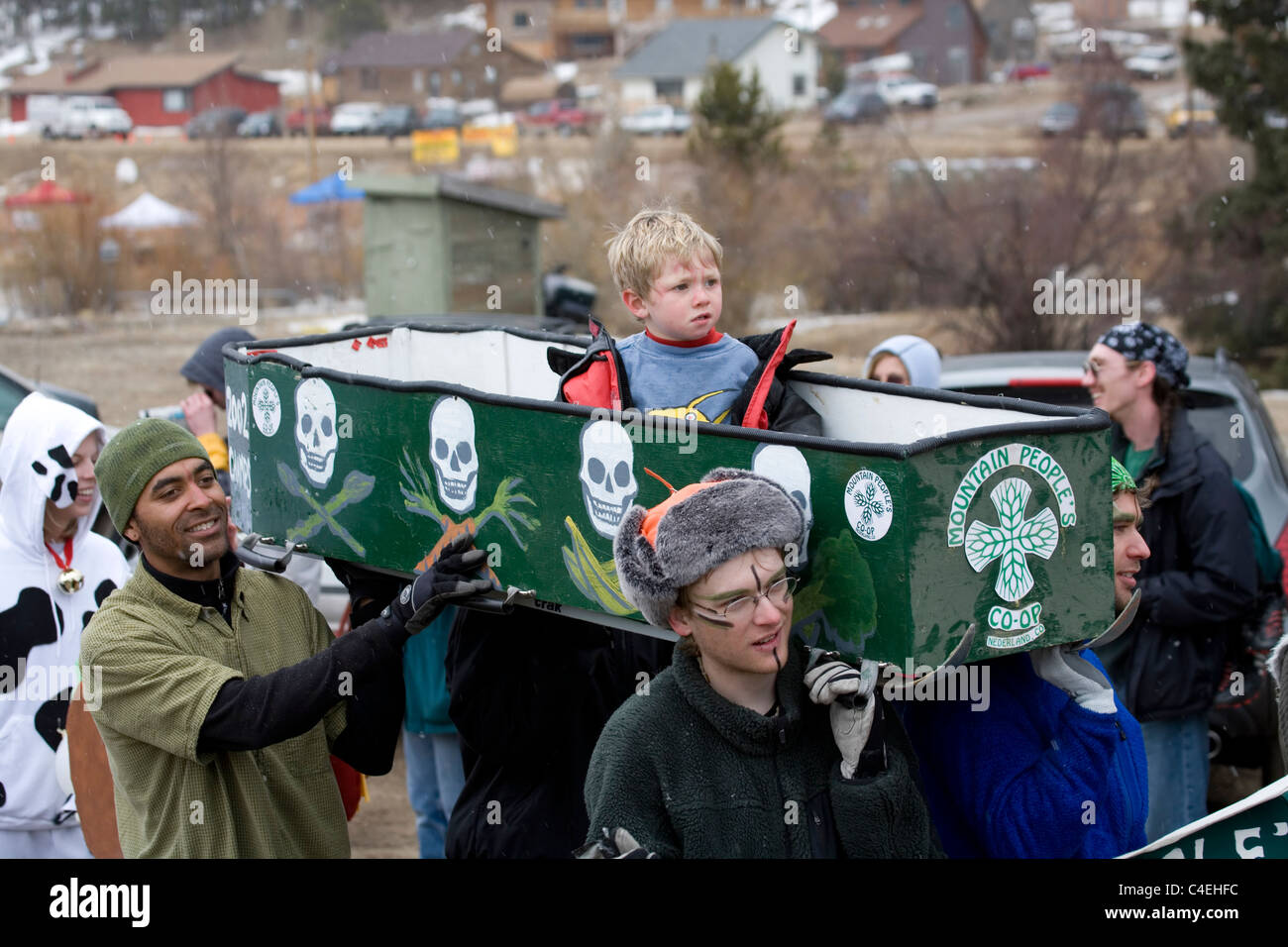 A boy in a coffin is carried in a parade procession prior to the races