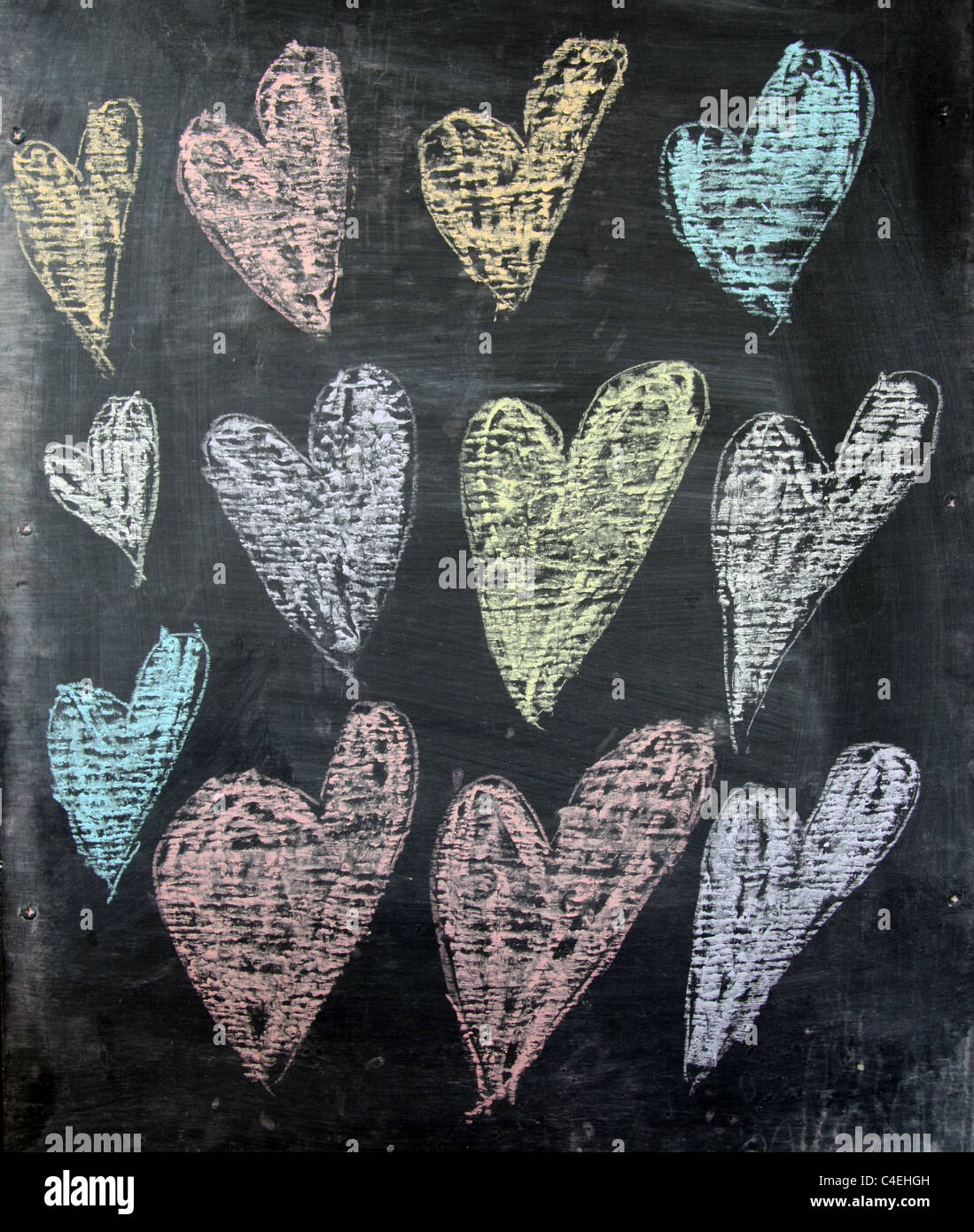 child's drawing of coloured love hearts in chalk on blackboard Stock Photo