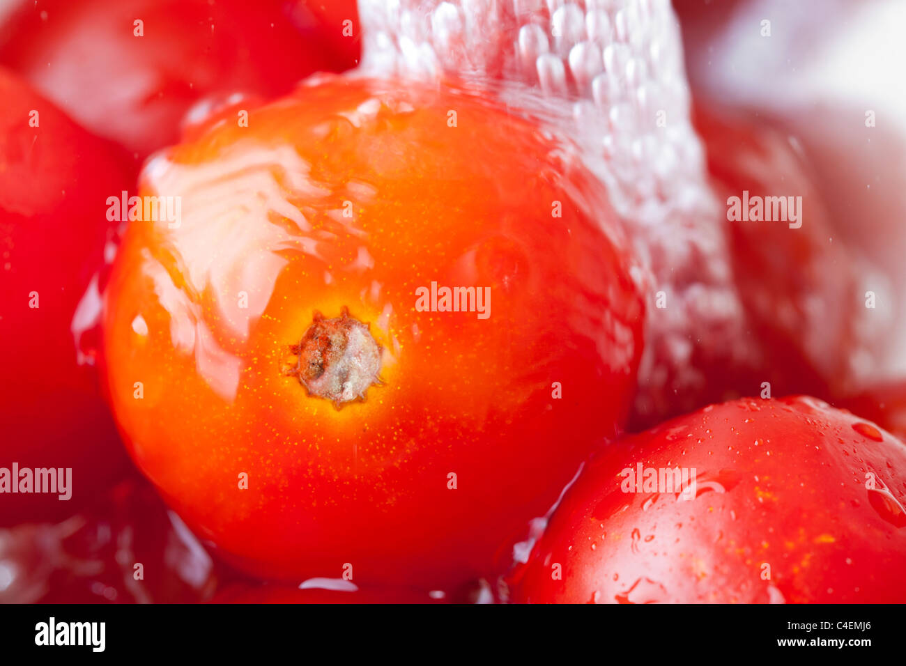 Red ripe tomatoes being washed with water Stock Photo
