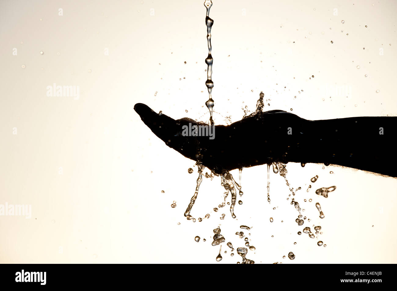 Water pouring and splashing on a hand. Silhouette Stock Photo