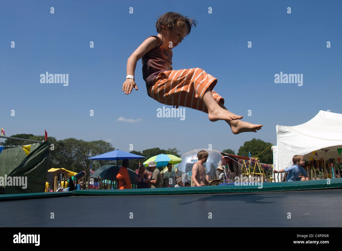 little boy on a trampoline in the kids field at glastonbury festival Stock  Photo - Alamy