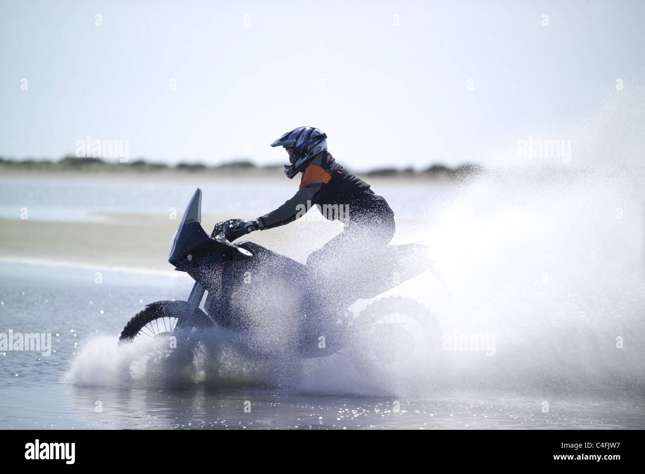 Motorcyclist driving through water Stock Photo