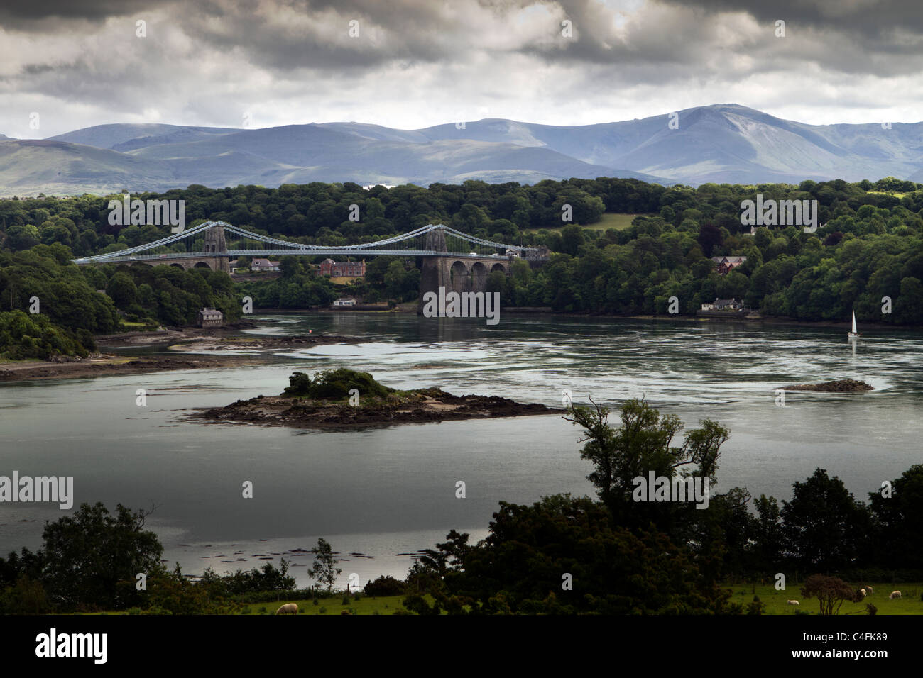 Menai Bridge across the  Menai Strait between Anglesey and mainland Wales, with the mountains of Snowdonia in the background Stock Photo