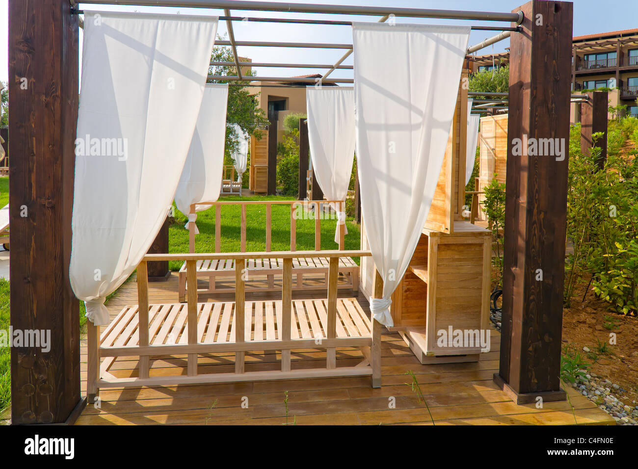 curtain-covered wooden recliners near the beach at resort Stock Photo