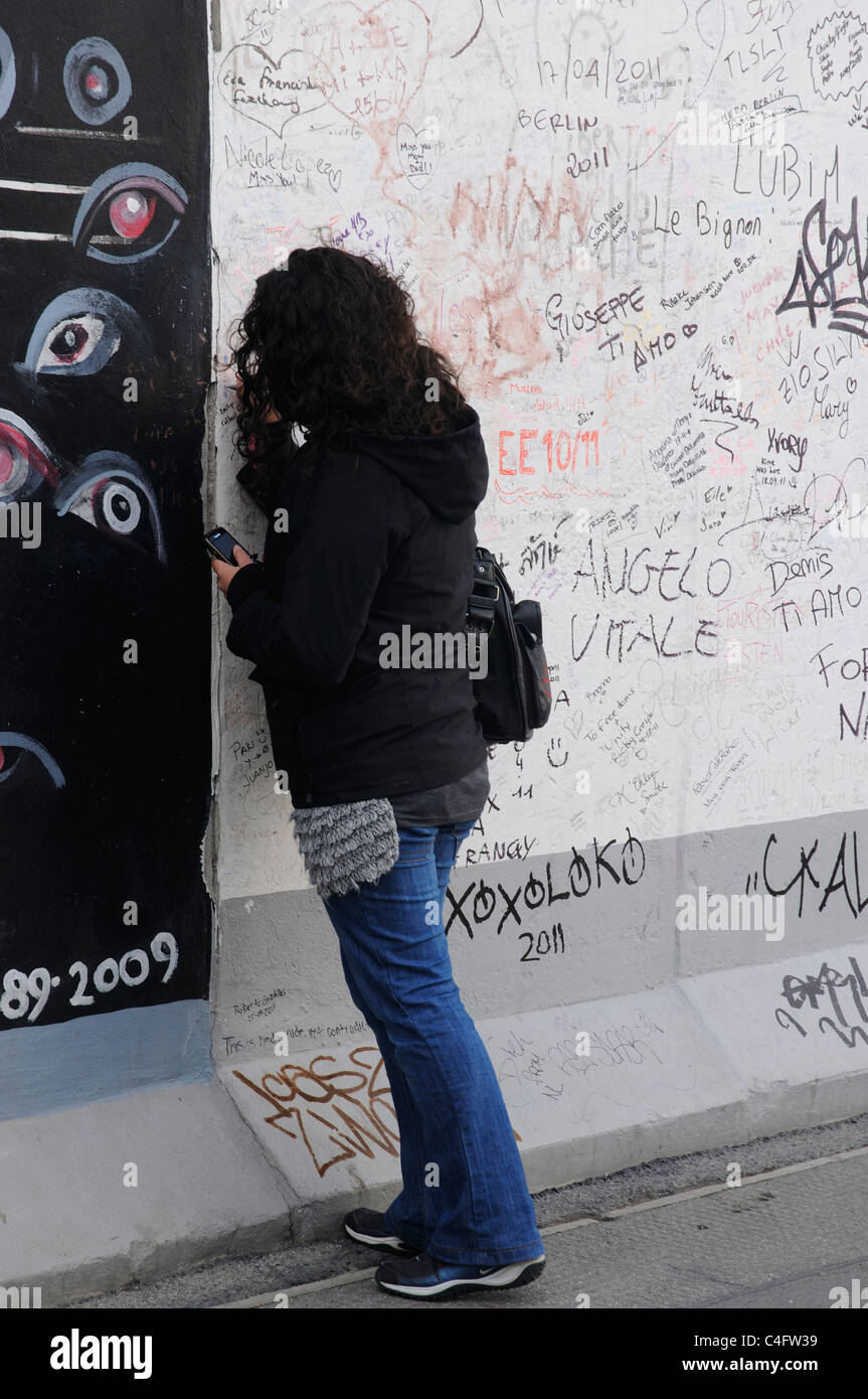 A girl writing on the Berlin Wall Stock Photo