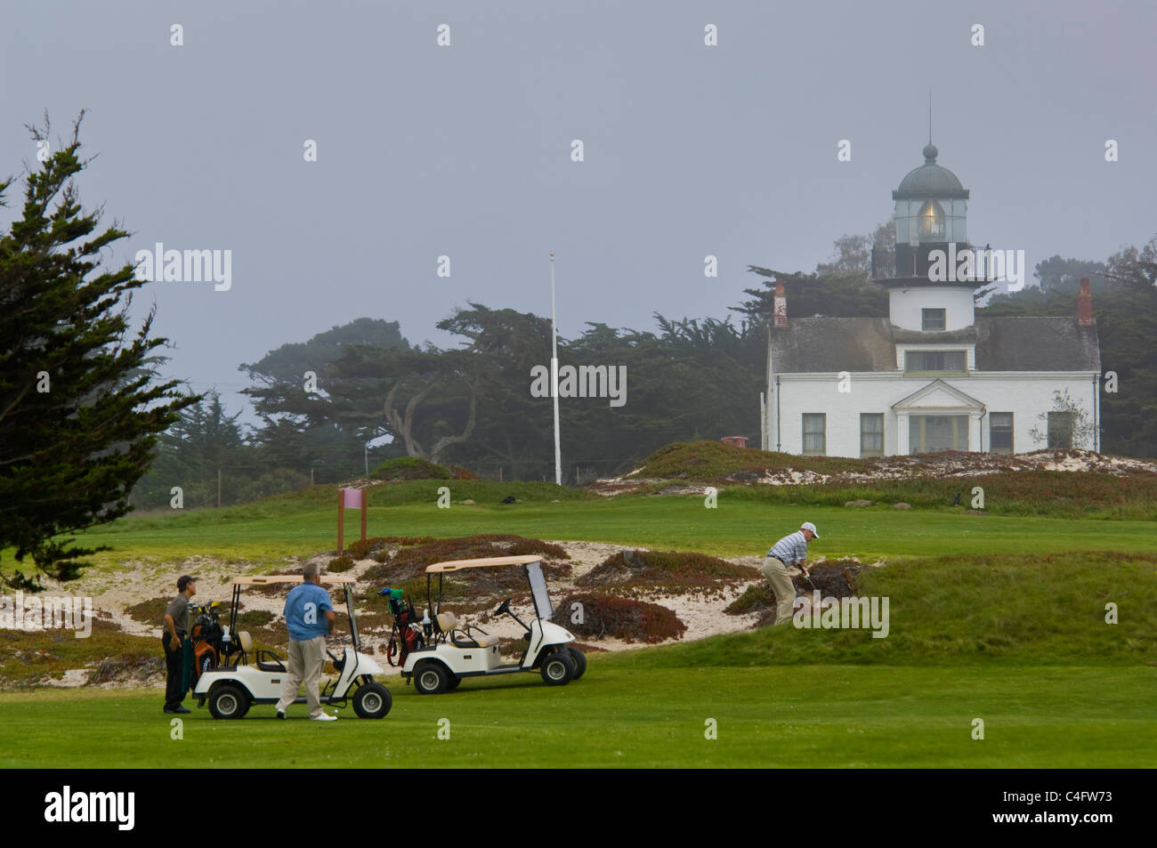 Golfers on golf course and Point Pinos Lighthouse in fog, Pacific Grove, Monterey Peninsula, California Stock Photo