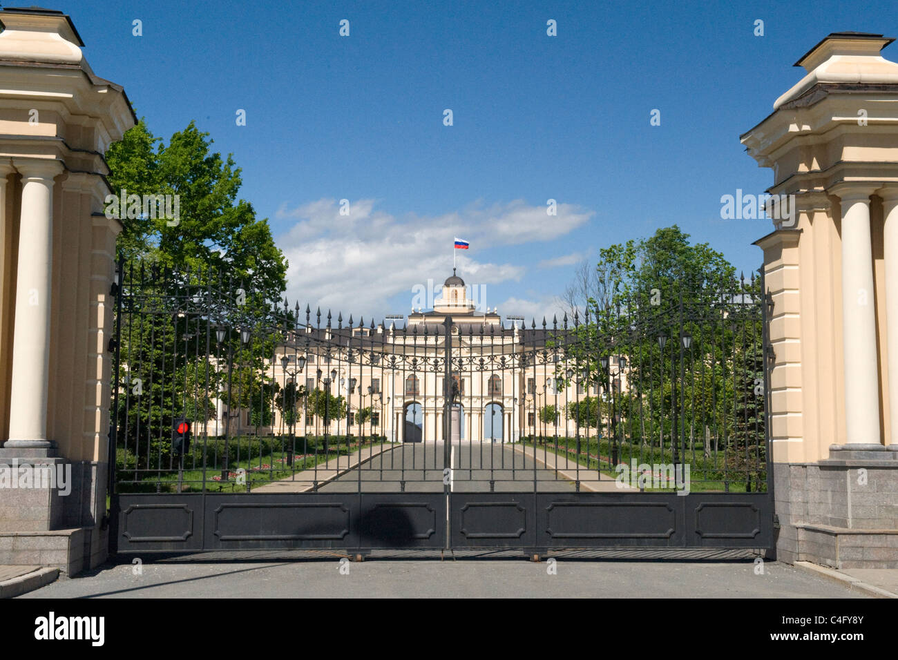 Russia St Petersburg President Vladimir Putin official summer residence or dacha black metal gates blue sky clouds trees drive flag flagpole Stock Photo