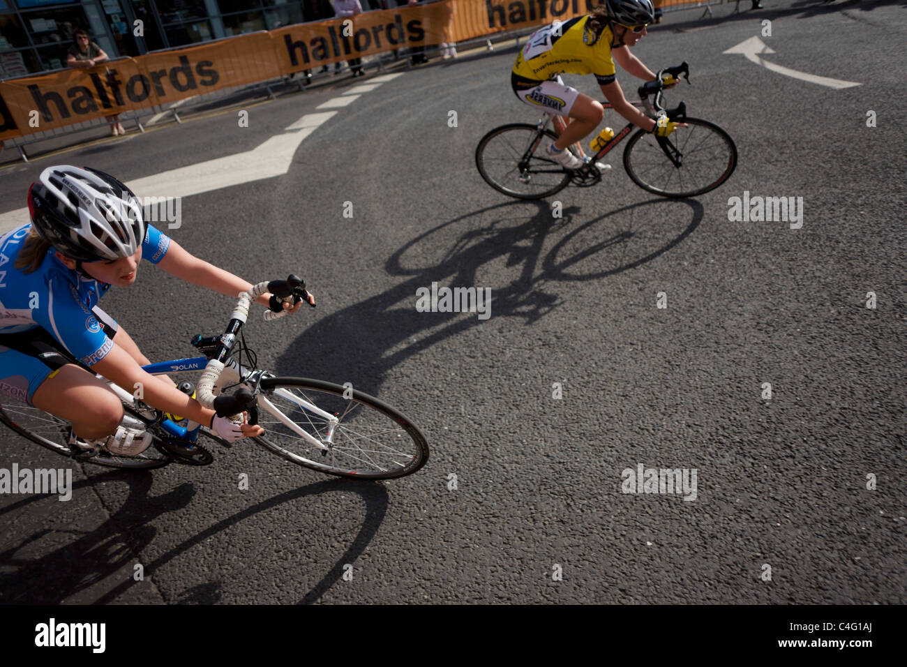 With bike shadows, speeding women cyclists turn into a corner of a