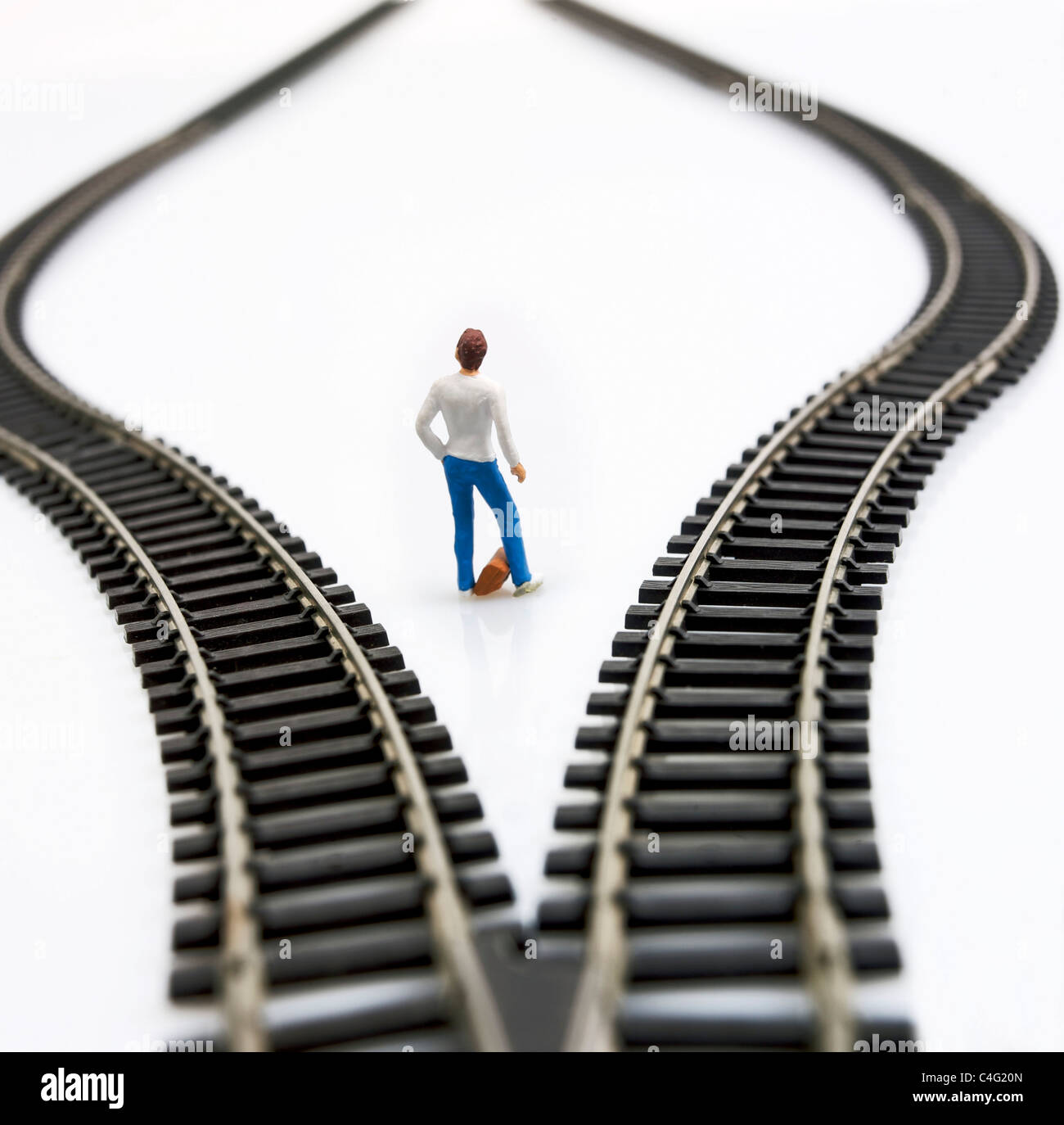 Figurine between two tracks leading into different directions, symbolic image for making decisions. Stock Photo
