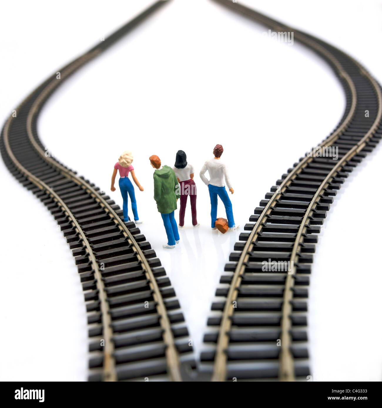 Young people figurines between two tracks leading into different directions, symbolic image for making decisions. Stock Photo