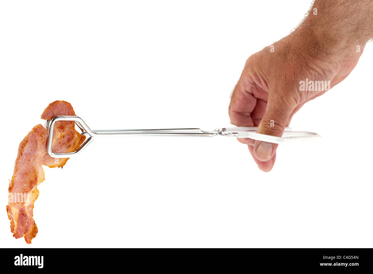 Single rasher of bacon picked up with a mans hand holding kitchen tongs Stock Photo