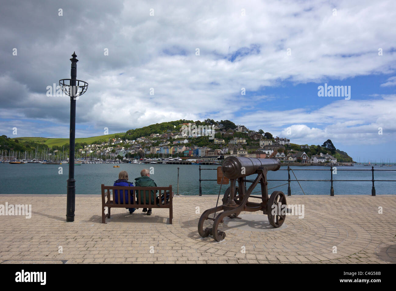 Middle-aged couple on seat and cannon, Dartmouth, South Devon England UK  United Kingdom GB British Isles Stock Photo