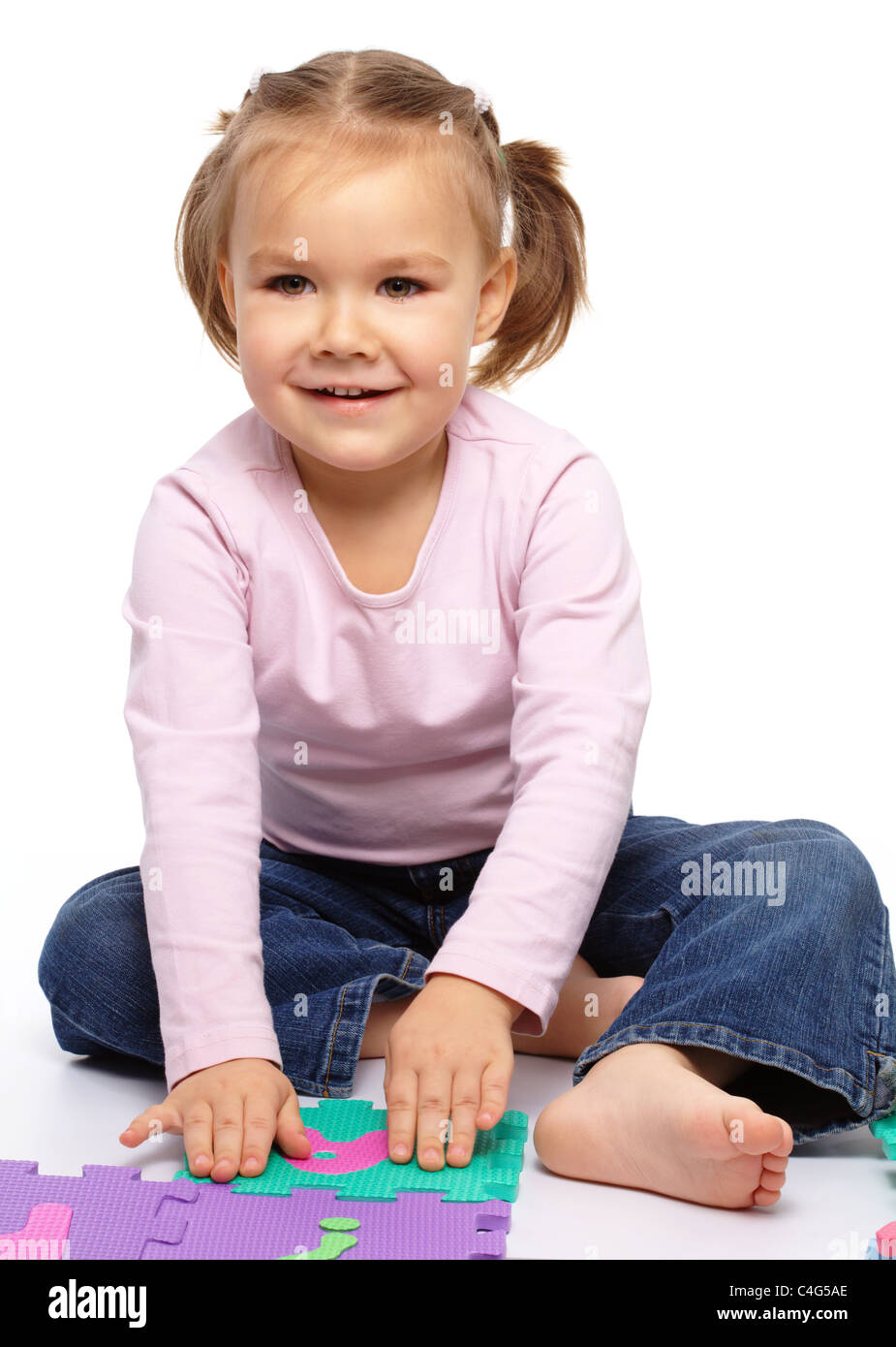 Cute little girl is playing with alphabet, putting hands up while