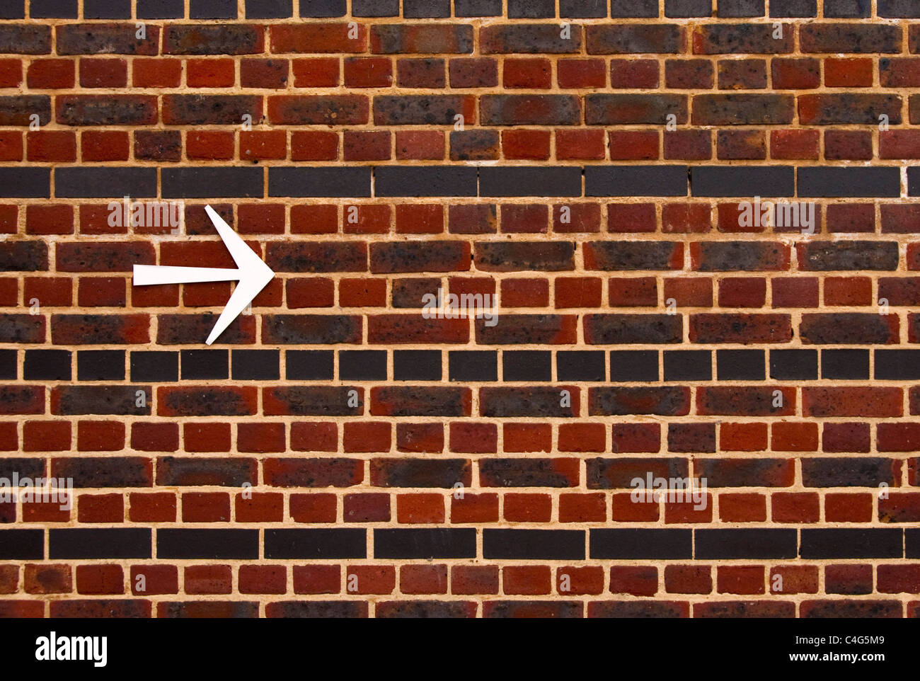 An arrow pointing the right direction on a brick wall Stock Photo