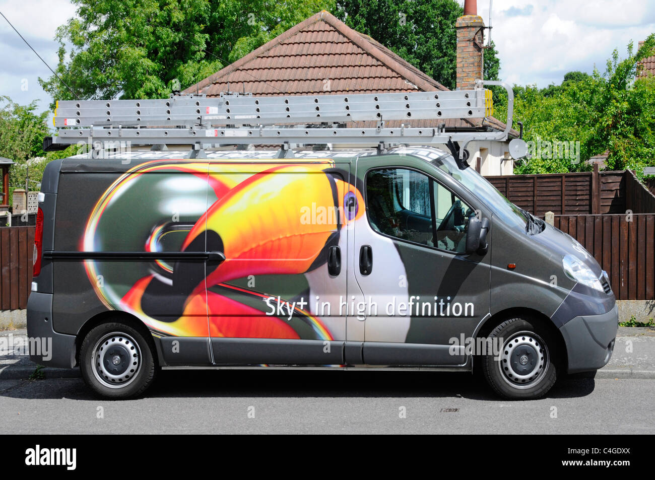 Sky TV television aerial installation engineer van & roof rack ladder parked in residential street with colourful graphic design on side England UK Stock Photo