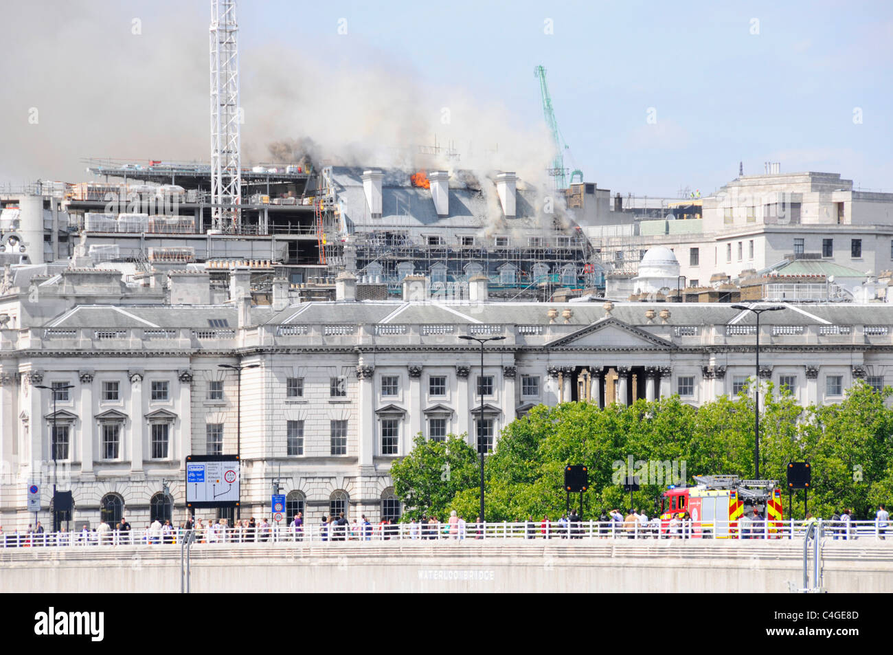 London fire brigade fire engine on way to Marconi House construction building site roof on fire Strand skyline seen beyond Somerset House England UK Stock Photo