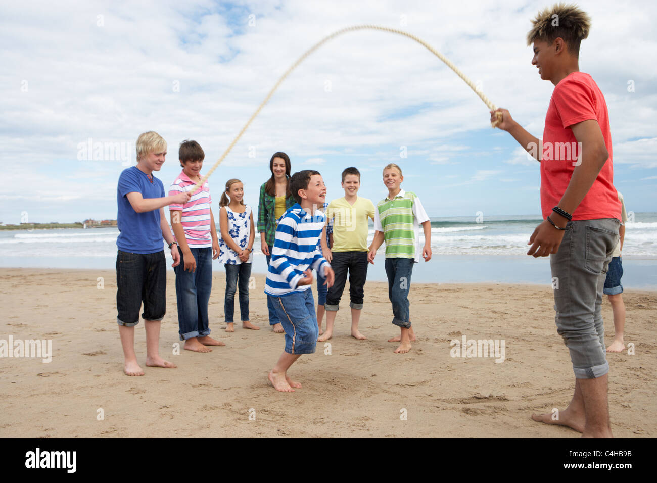 Teenagers playing skipping rope Stock Photo