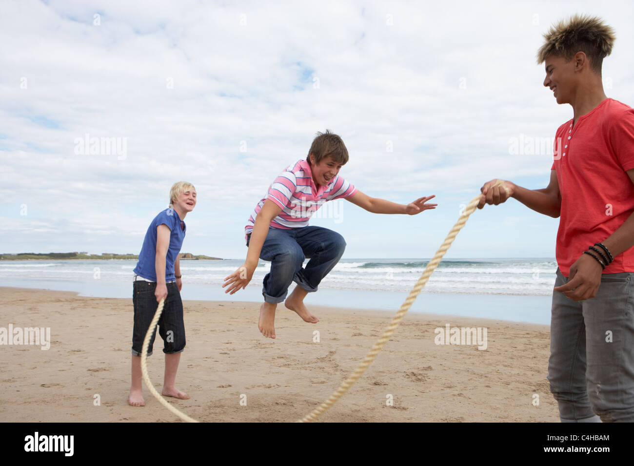 Teenagers playing skipping rope Stock Photo