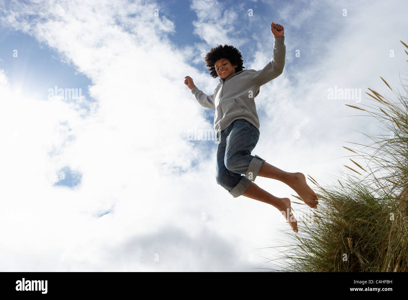 Boy jumping over dune Stock Photo