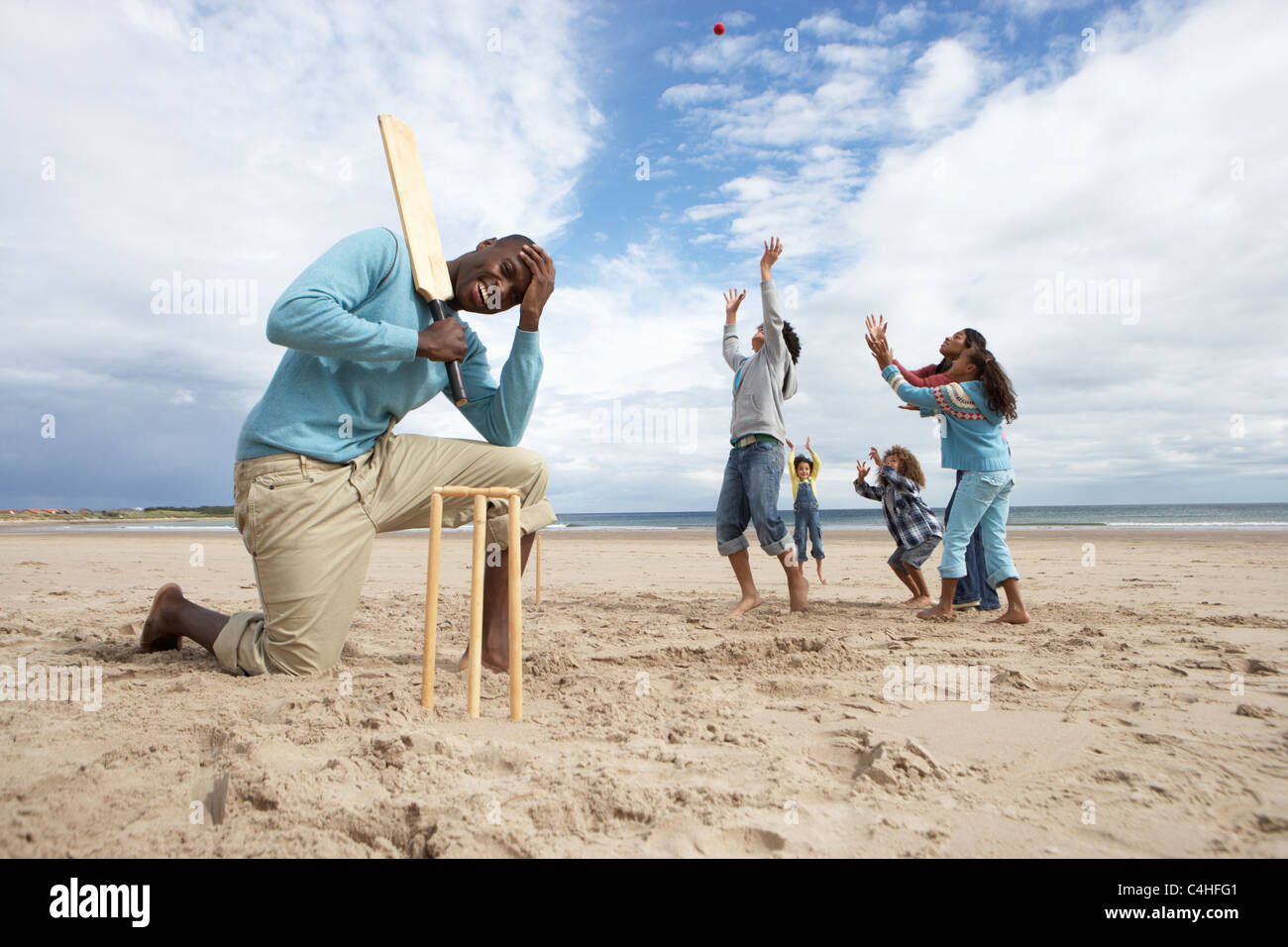 Family playing cricket on beach Stock Photo