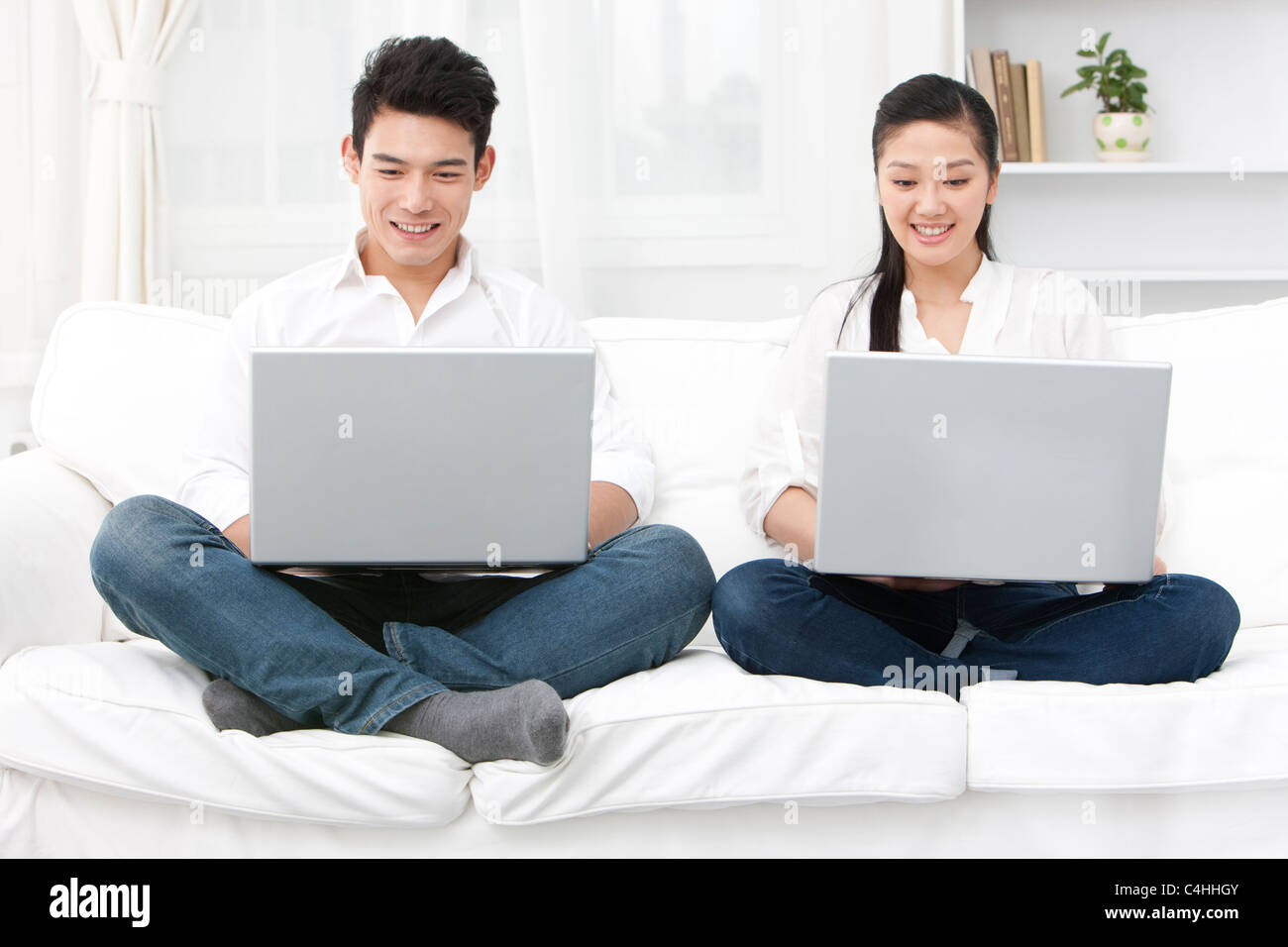 Happy young couple using laptop together Stock Photo - Alamy