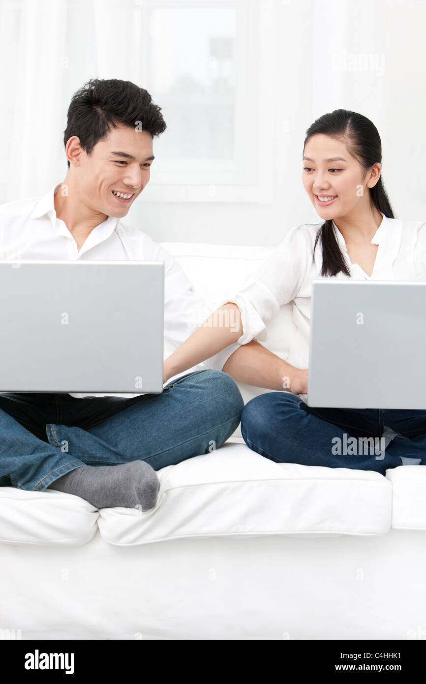 Happy young couple using laptop together Stock Photo - Alamy