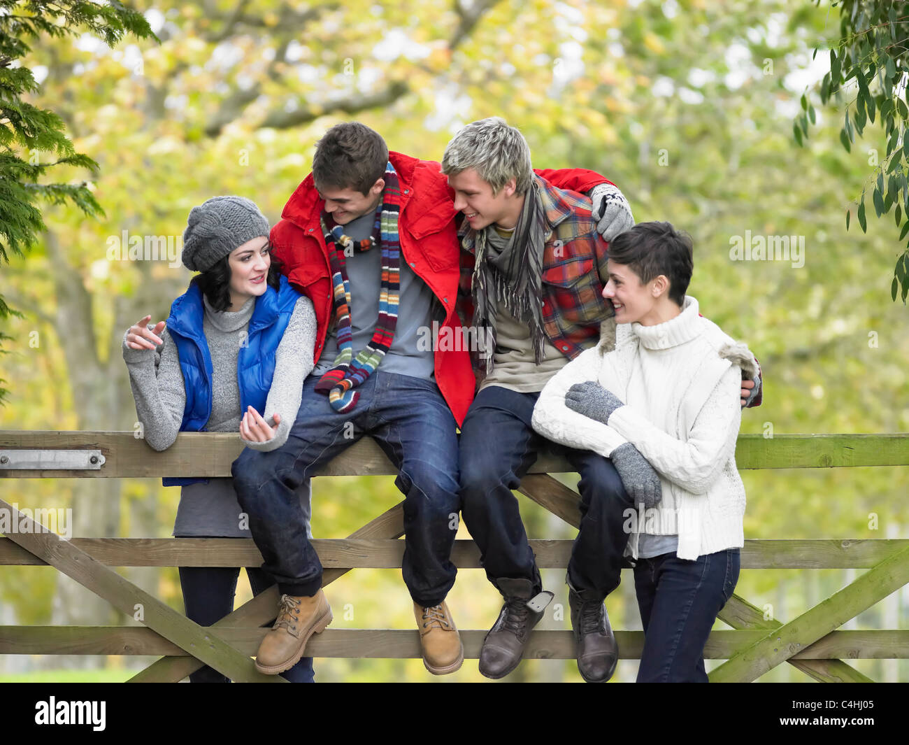 Young friends sitting on fence Stock Photo