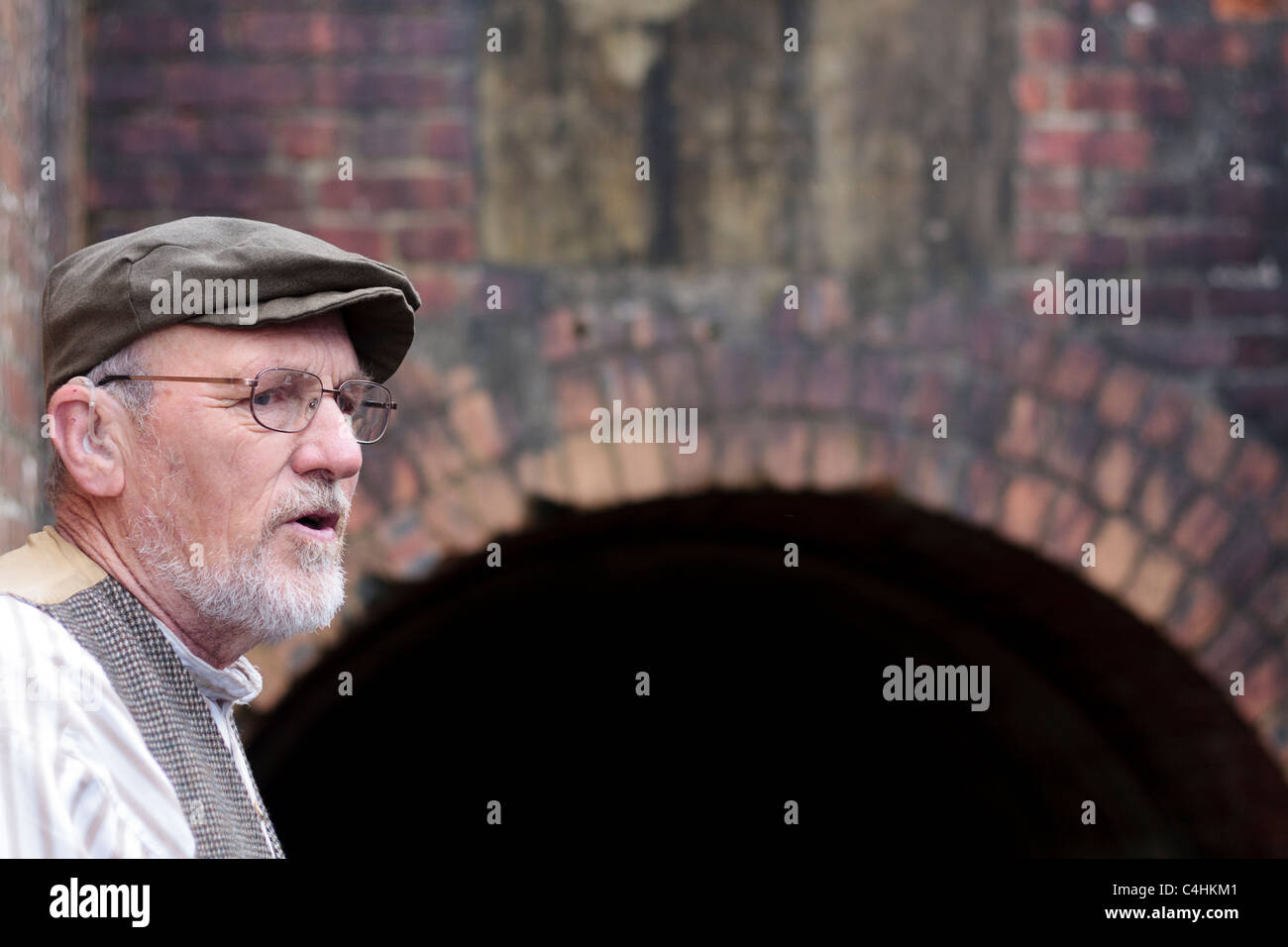 A retired old miner talks about life down the pit at the entrance to the pit in Beamish museum, Durham, England Stock Photo