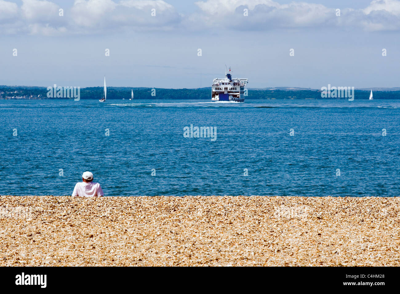 man sitting on beach looking at ship out to sea Stock Photo - Alamy