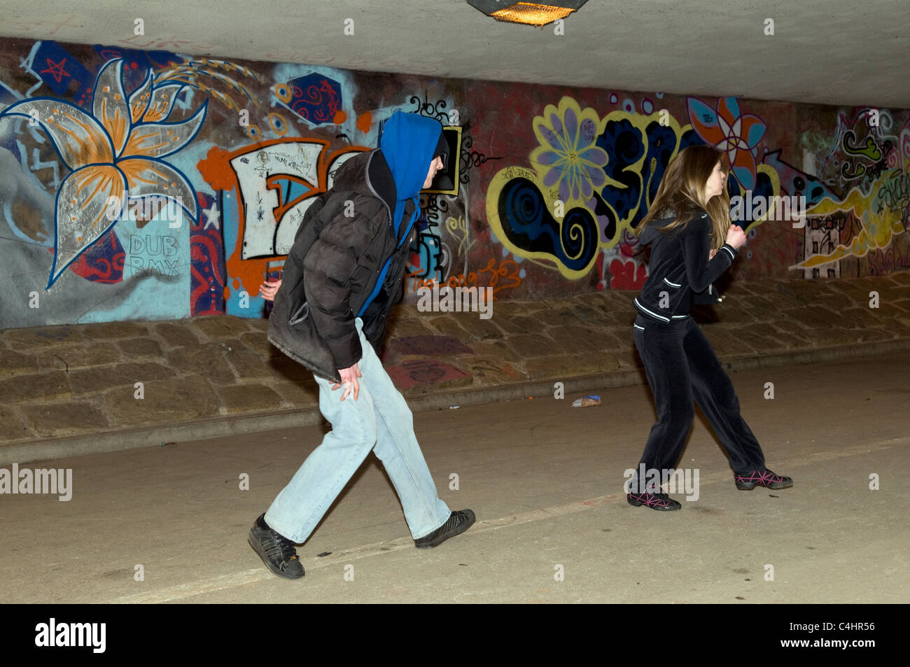 Scene showing young Caucasian woman defending herself with tae kwon doing martial arts against attacker in underpass in Bristol Stock Photo